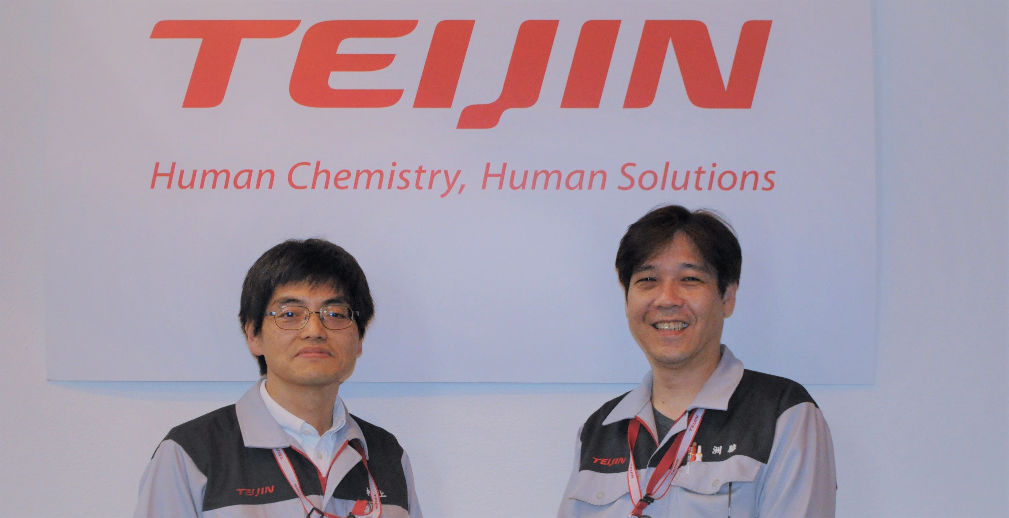 帝人ファーマ株式会社 東京研究センターのロゴを背景にして社員2名が撮影された写真