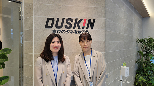 株式会社ダスキンのロゴを背景にして、社員2名が撮影された写真